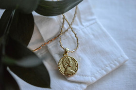 Lasihelmi kaulakoru kullatulla kolikko riipuksella.