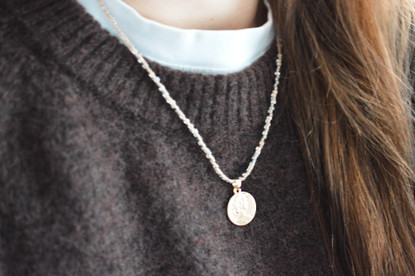 Lasihelmi kaulakoru kullatulla kolikko riipuksella.