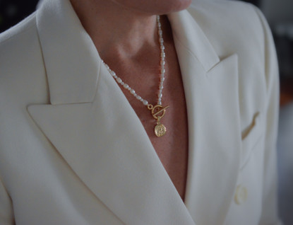 Helmikaulakoru kullatulla kolikko riipuksella.