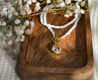 Helmikaulakoru kullatulla lasiriipuksella. 