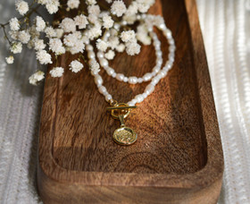 Helmikaulakoru kullatulla kolikko riipuksella.